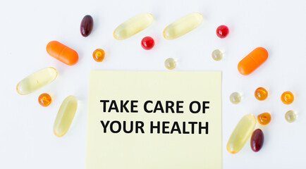 medicine and health concept. Take care of your health text on a yellow sticker on a white background, multi-colored pills are scattered nearby