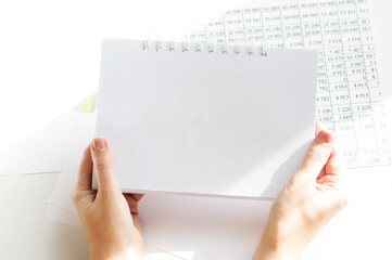 on the background of the table, the girl's hands hold a notebook, empty for writing down the text