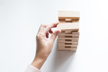 human hand builds a tower of wooden blocks as a symbol of development and planning in business, a strategy for success