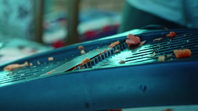 Close up view of cook graating carrot. Refugee cooks pilaf.