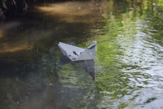 A smoking paper boat floating on a forest river.