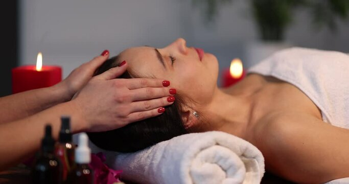 Masseuse makes face massage to woman in spa closeup