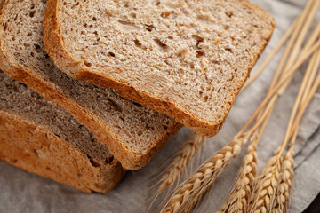 Fresh baked sliced loaf of rye bread on a brown background
