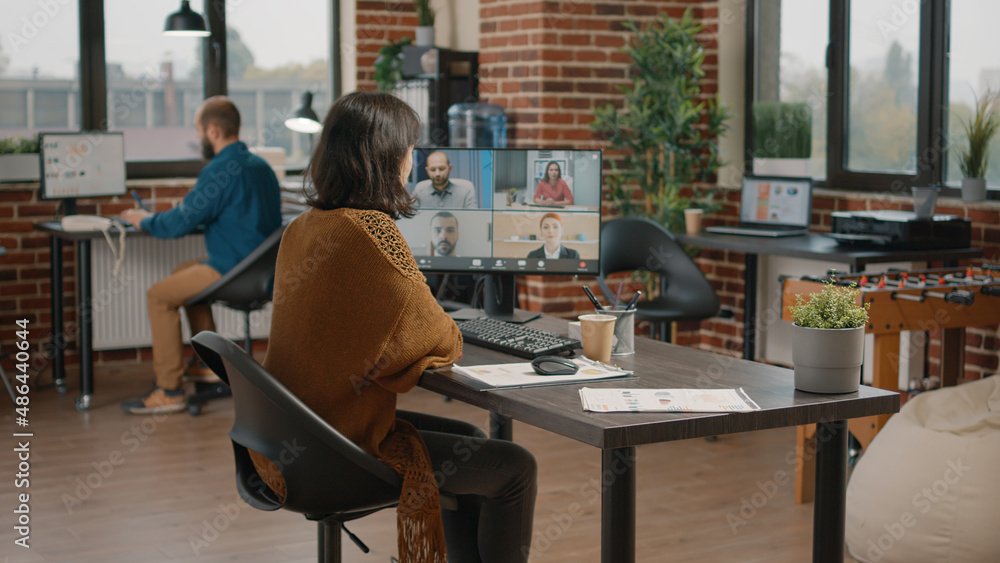 Poster employee using video call on computer to talk to workmates about project planning and marketing stra