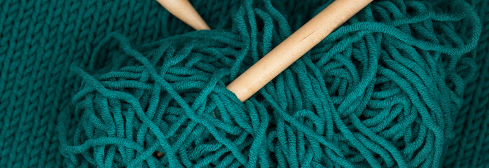 Wooden knitting needles stuck into a skein of blue wool.