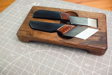 Exclusive handmade leather craft tools. Set of knifes from steel and wood. Close up of different tanner tools on wooden box. 
