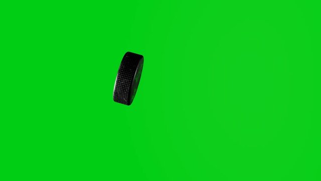 Hockey puck flies into camera on chromakey background. Sports concept.