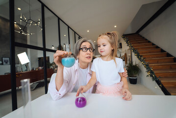 Attentive old grandma assist grandkid in funny scientific research