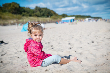 Little girl is sitting on the beach near Hel city. Poland