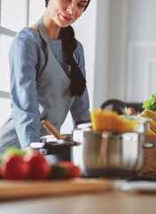 Young woman holding grocery shopping bag with vegetables .Standing in the kitchen