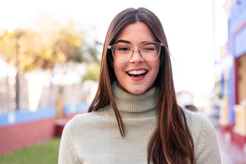 Young Brazilian woman at outdoors With glasses and happy expression