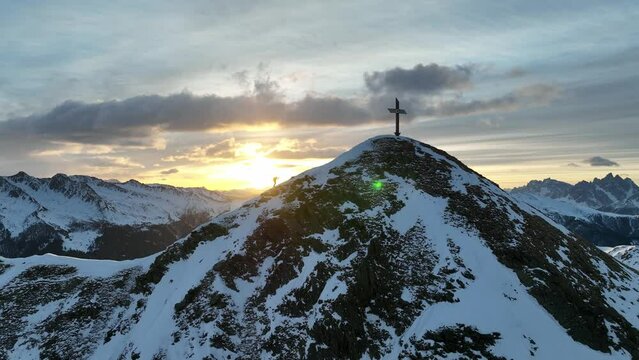 Mountaineer climbs the last meters to the summit during sunrise in the Italian Alps