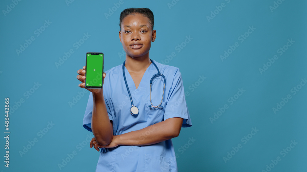 Poster portrait of medical assistant holding smartphone with green screen. woman nurse showing device with 