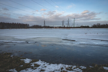 high voltage electric power lines in flood region, Jelgava, Latvia, melting snow, blue sky with...