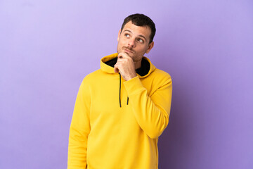 Brazilian man over isolated purple background and looking up