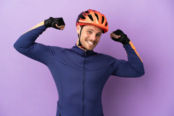 Young Brazilian cyclist man isolated on purple background doing strong gesture - obrazy, fototapety, plakaty