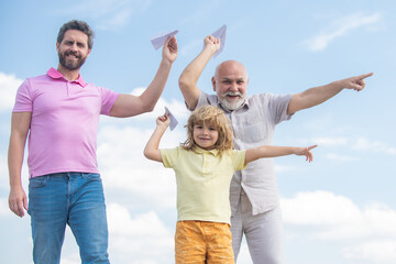 Three generations of men together, portrait of smiling son, father and grandfather with a toy airplane. Child boy playing with plane and dreaming future.