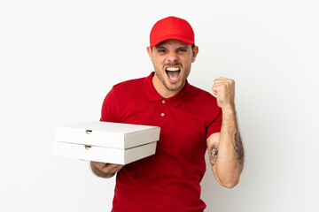 pizza delivery man with work uniform picking up pizza boxes over isolated  white wall celebrating a victory in winner position