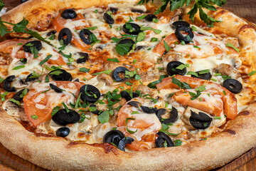 Pizza with bacon and cheese, herbs and cherry tomatoes. With mozzarella, shrimps and octopuses, mussels and other products on a wooden background.