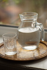 Jug of water and a glass on the windowsill.