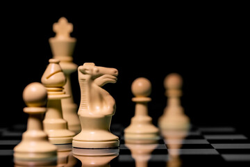 Close up of Chess pieces on a reflective mirror board surface with black background