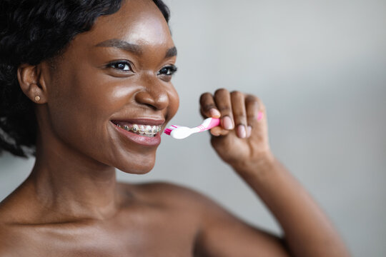 Closeup Of Young Black Woman With Braces Brushing Her Teeth