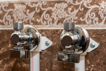 Water taps for connecting a boiler on tiled wall. The faucet with connected pipes is mounted on the wall. Close up