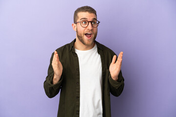Fototapeta premium Young handsome caucasian man isolated on purple background with surprise facial expression