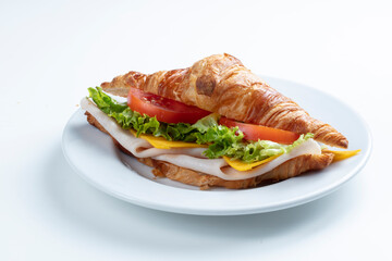 Croissant de jamón queso y  verduras sobre fondo blanco. Croissant with ham cheese and vegetables on white background.