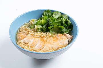 Pollo con tallarines  y verduras en bol azul. Chicken with noodles and vegetables in a blue bowl.