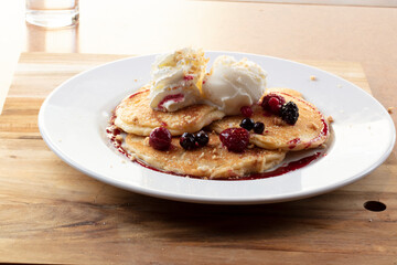 Tortitas con nata y frutos del bosque. Pancakes with cream and berries on wooden table.
