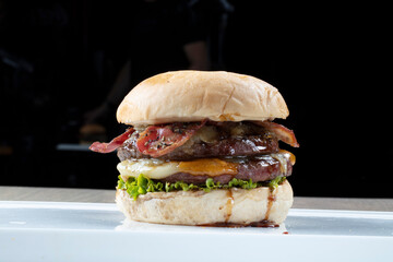 Hamburguesa de carne sobre fondo negro, de cerca. Beef burger on a black background, close up.
