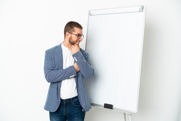 Young handsome caucasian man isolated on white background giving a presentation on white board and looking side