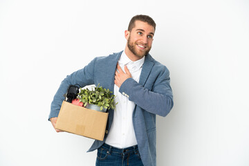 Young caucasian making a move while picking up a box full of things isolated on white background looking up while smiling