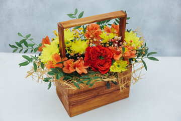Bouquet of chrysanthemum peony rose and alstroemeria in a wooden gift box on a gray background. Available in red, orange and yellow.