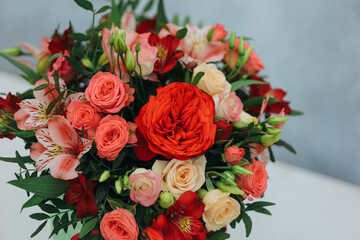 Red bouquet of rose, alstroemeria and eustoma in a green paper gift box on a gray background. Close up