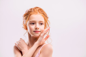 Portrait of a little red-haired girl ballerina on a white