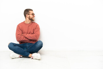Young handsome man sitting on the floor happy and smiling