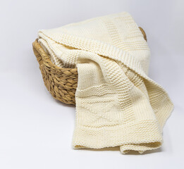 White merino wool knitted blanket in geometric pattern in basket on white background