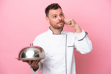 Young Brazilian chef with tray isolated on pink background having doubts and thinking