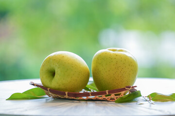 Fresh Yellow Apple in wooden basket, Golden yellow Ohrin Apple  in the basket over green natural Blur background.