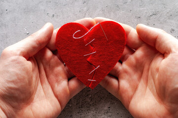 holds in his hands a broken heart sewn with threads concept broken love, divorce