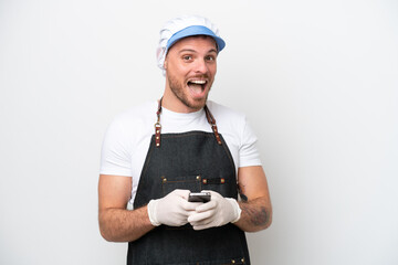 Fishmonger man wearing an apron isolated on white background surprised and sending a message