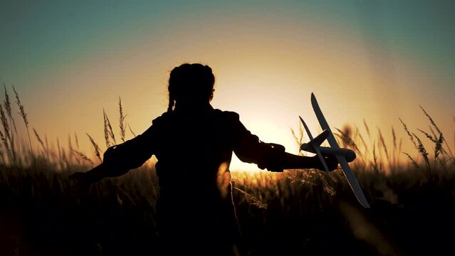 Happy girl with oy in natural park. Child runs on grass with an airplane. Chidhood dream. Happy baby girl with toy airplane at sunset. Child runs on grass in field. Dream travel concept