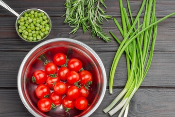 Tomatoes and fresh green peas in metal bowls.