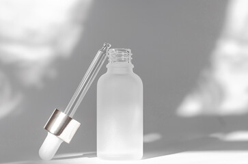 White cosmetic bottle with essential oil on a white background with shadows. Cosmetic branding mockup. Skin care concept