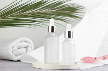 SPA composition. Two white bottles with essential oil or serum on a podium. massage set