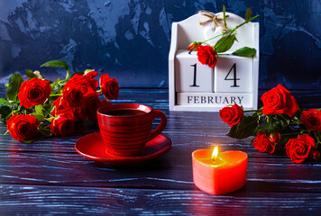 Valentine's Day is a calendar date in February. Red cup of coffee, lighted candle in the form of heart, a bouquet of red roses. Romantic celebration. Side view.