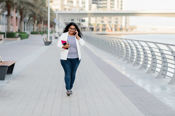 An Indian girl is walking around the city and talking on the phone.