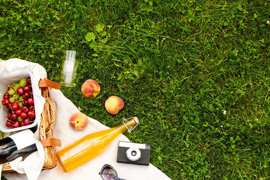 leisure, food and drinks concept - close up of picnic basket, bottle of fruit juice with sunglasses and film camera on grass - Powered by Adobe